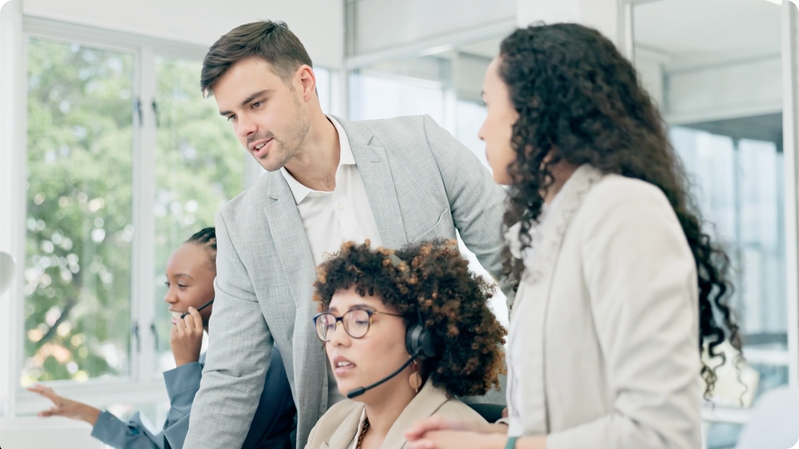 Sales team engaged in coaching session with headset-wearing team member and manager, promoting a sales coaching demo.